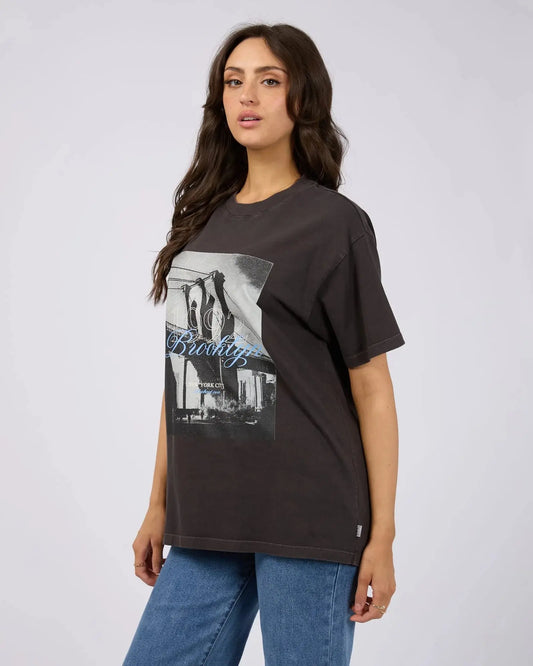 Woman wearing a black t-shirt with a graphic design on a plain background