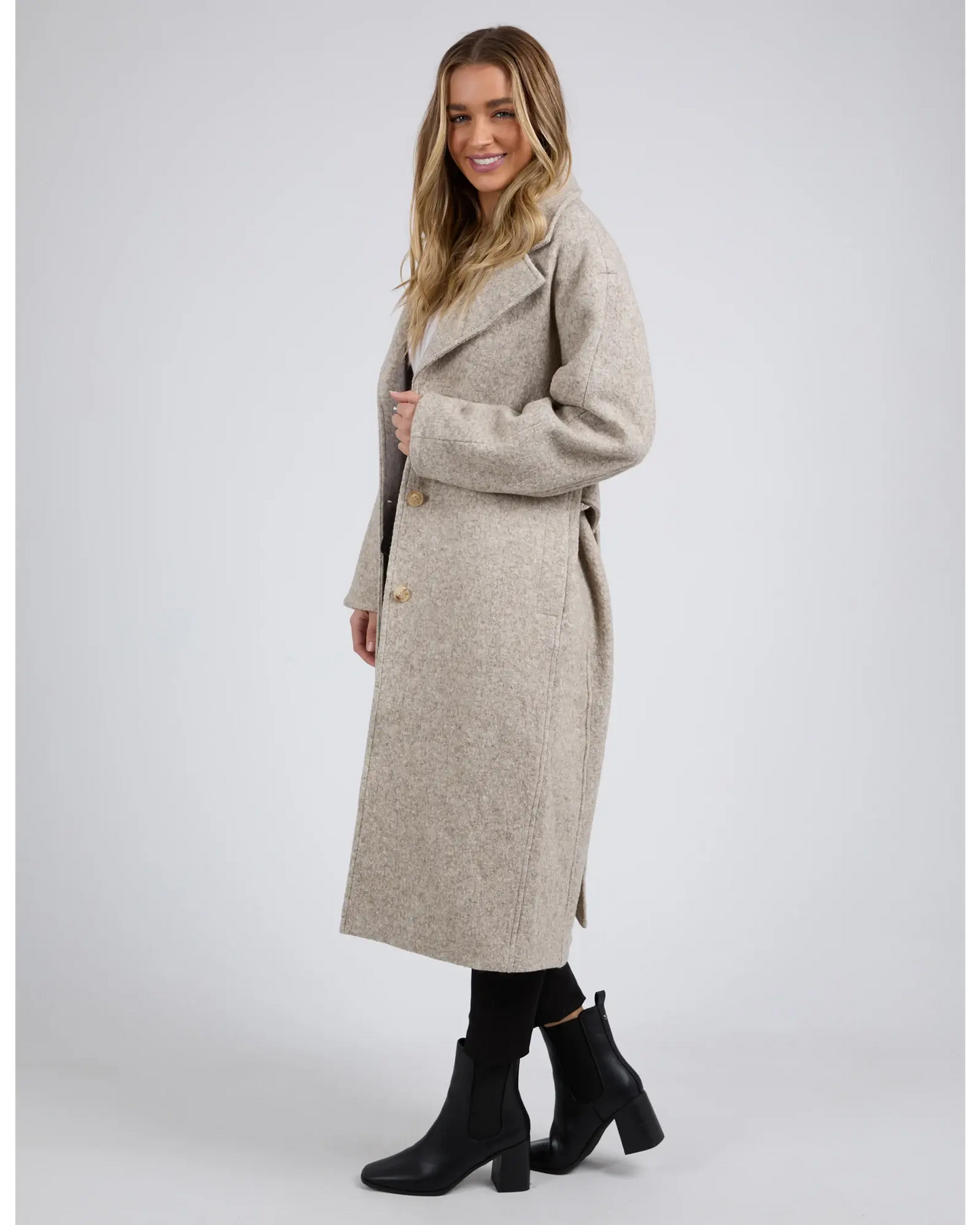 Woman wearing a long beige coat on a white background