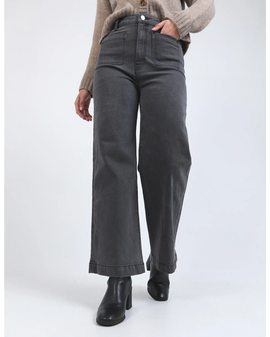 Person wearing dark gray wide-leg jeans on a white background