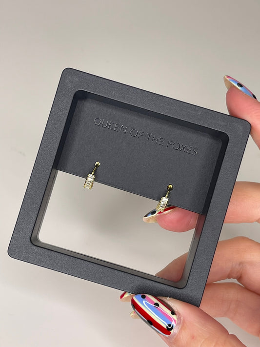 Black earring display stand with 'Queen of the Foxes' branding, held by a hand. Petite Sleepers Marquise - The Rose Edit