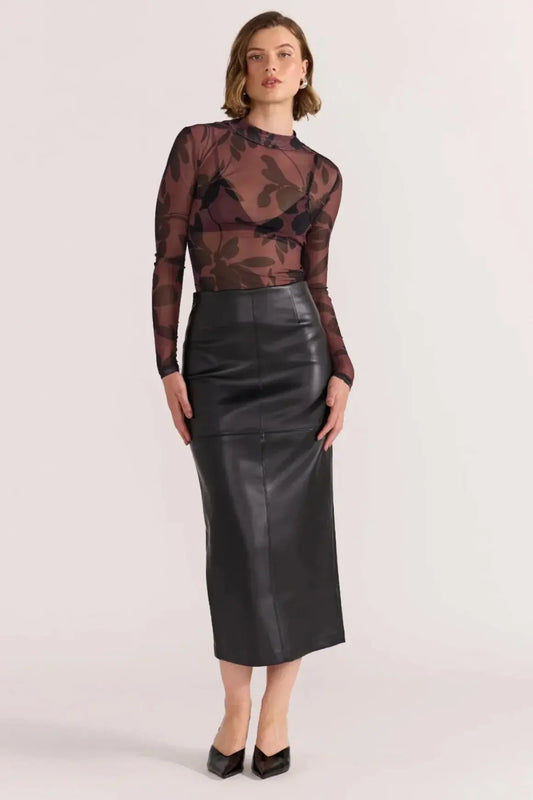 Woman wearing a patterned top and black leather skirt on a white background