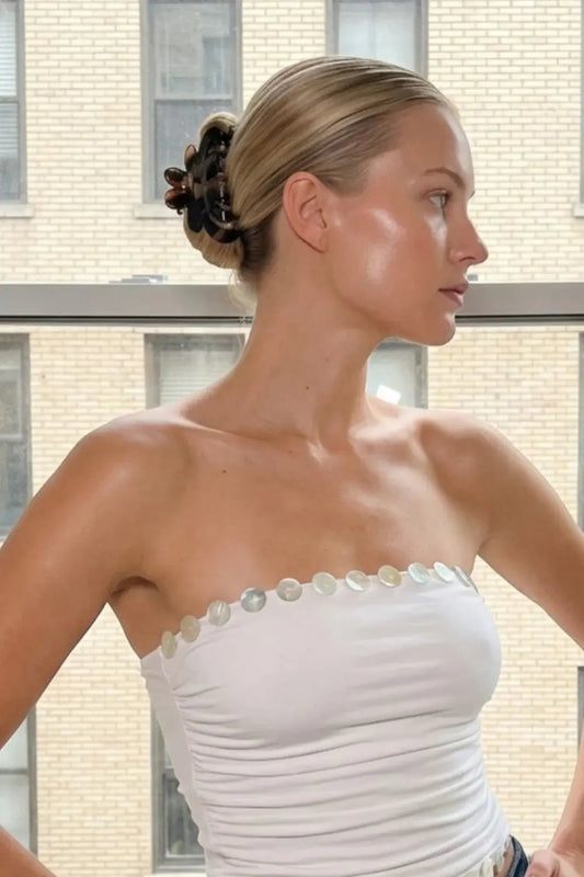 Woman wearing a strapless white dress with pearl embellishments in front of a window. Buttermilk Rebekah Claw Clip Coffee Table - The Rose Edit