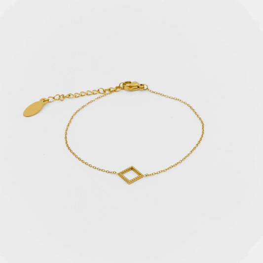 Gold bracelet with a geometric design on a light gray background