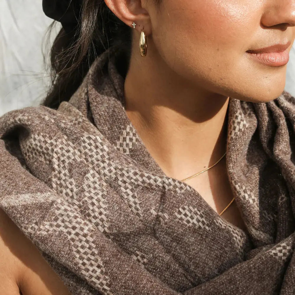 Close-up of a person wearing a brown patterned scarf with a neutral background