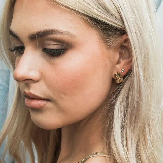 Close-up of a woman wearing gold earrings with a blurred background