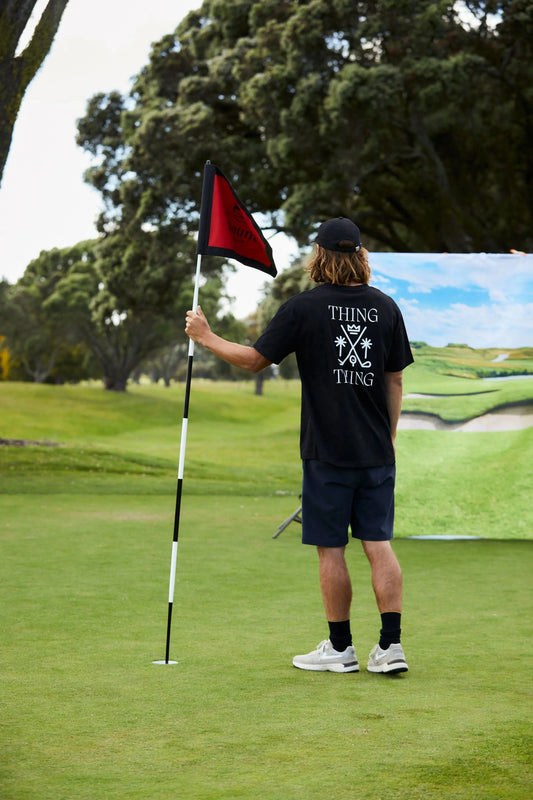 Person on a golf course holding a flag, with a scenic background