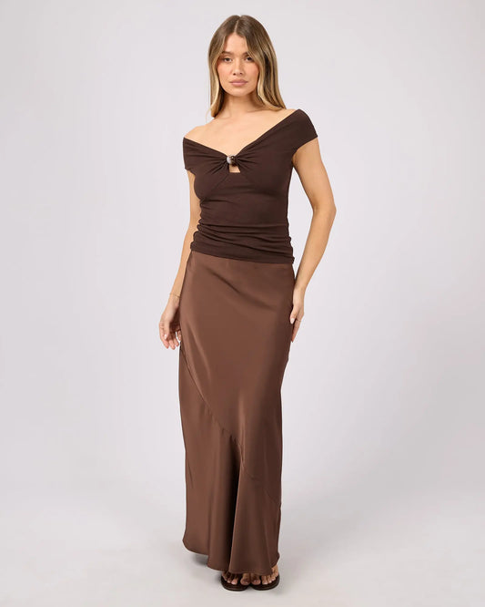 Woman wearing a brown off-shoulder dress on a white background. Carter Maxi Skirt Brown - The Rose Edit