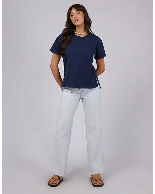 Woman wearing a navy blue t-shirt and light blue jeans on a gray background