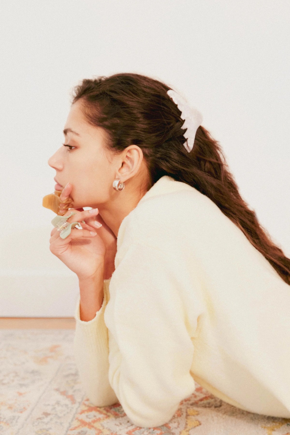 Woman in a white outfit lying on a patterned rug eating a piece of cake. Buttermilk Georgia Claw Clip Classic Pearl - The Rose Edit