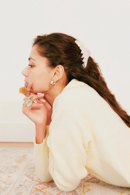 Woman in a white outfit lying on a patterned rug eating a piece of cake. Buttermilk Georgia Claw Clip Classic Pearl - The Rose Edit