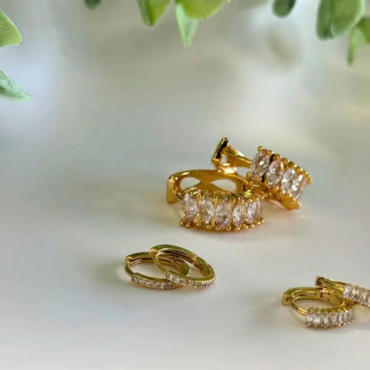 Gold hoop earrings with clear gemstones on a light background