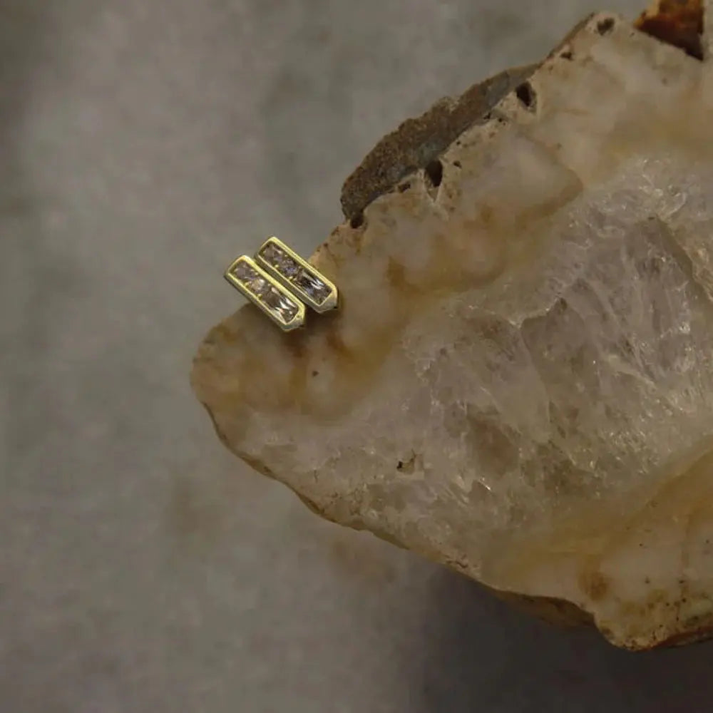 Gold earring with small diamonds on a rough stone surface