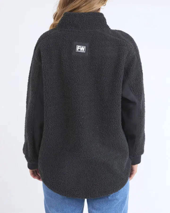 Person wearing a black fleece pullover with a logo on the back against a white background