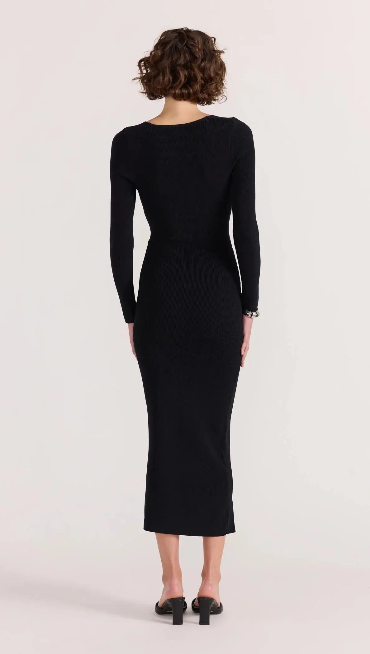 Person wearing a black dress with long sleeves on a white background