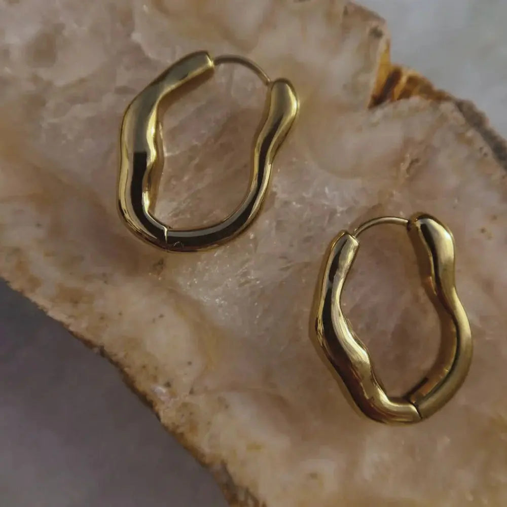 Gold hoop earrings on a textured beige surface