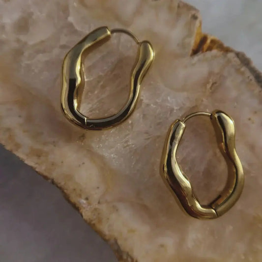 Gold hoop earrings on a textured beige surface
