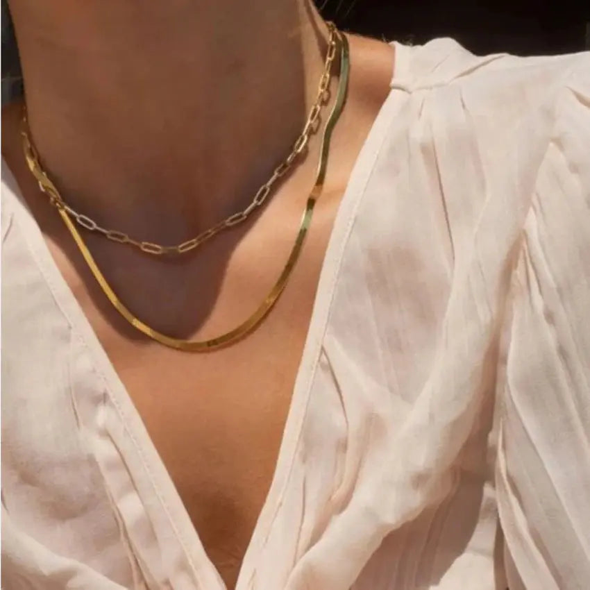 Gold chain necklace worn by a person in a light-colored garment