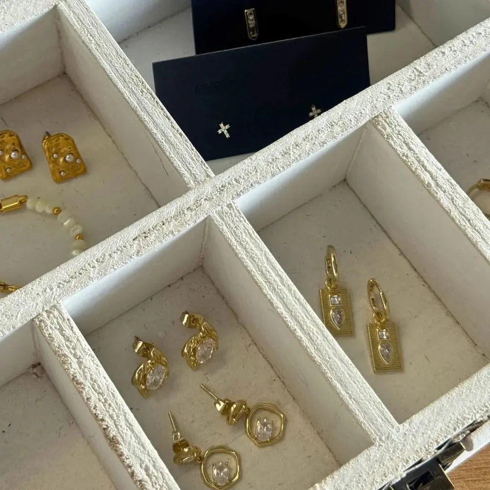 Gold earrings in a jewelry box with a white interior