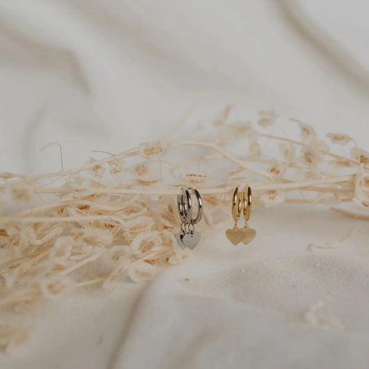 Silver and gold heart hoop earrings flat lay on dried floral linen texture. heart hoop earrings KatyB Jewellery