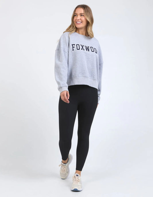Woman wearing a gray sweatshirt with 'FOXWOOD' text and black leggings on a white background