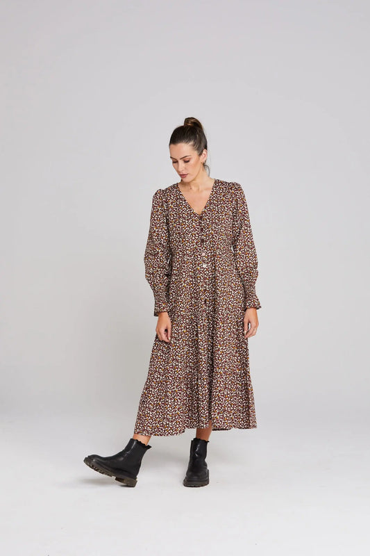 Woman wearing a brown patterned dress on a white background