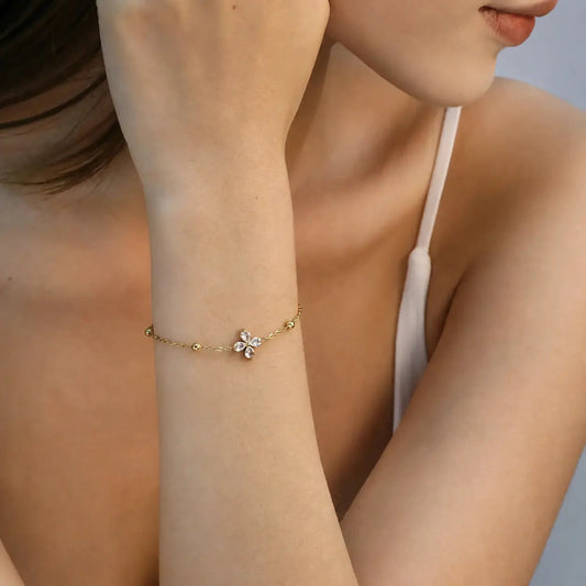 Woman wearing a delicate gold flower bracelet on her wrist.