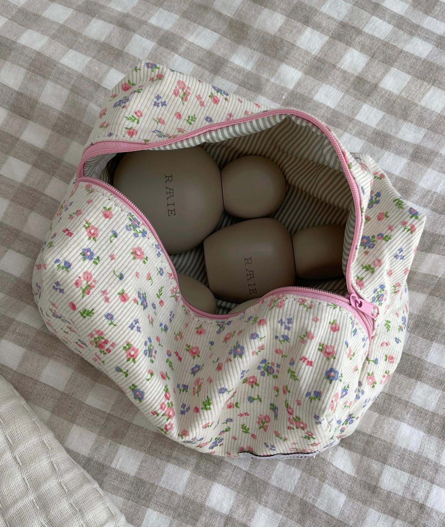 Floral-patterned bag with eggs on a checkered fabric background. Buttermilk Grace Carry All Bag Forget-Me-Not - The Rose Edit