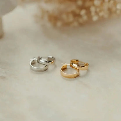 Gold and silver Aria Hoops flat lay on marble surface with dried florals