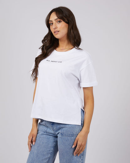 Woman wearing a white t-shirt with text and blue jeans on a plain background