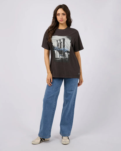 Woman wearing a black t-shirt with a graphic design and blue jeans on a white background