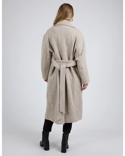 Woman wearing a beige coat with a belt on a white background