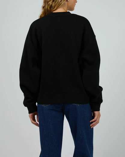 Person wearing a black sweatshirt and blue jeans on a plain background
