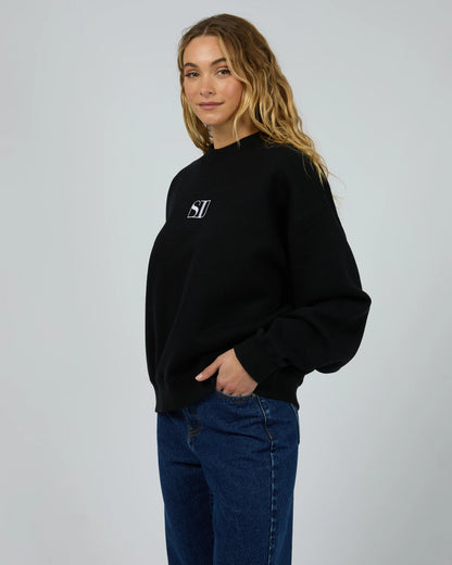 Person wearing a black sweatshirt with a logo on a gray background