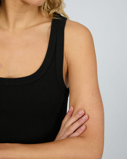Person wearing a black tank top against a plain background