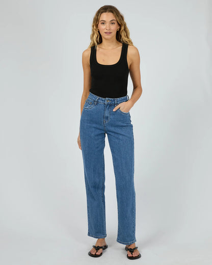 Woman wearing blue jeans and a black tank top on a white background