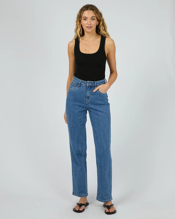 Woman wearing blue jeans and a black tank top on a white background