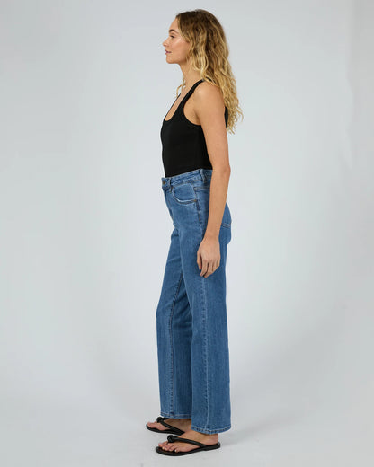 Woman wearing blue jeans and a black top on a white background