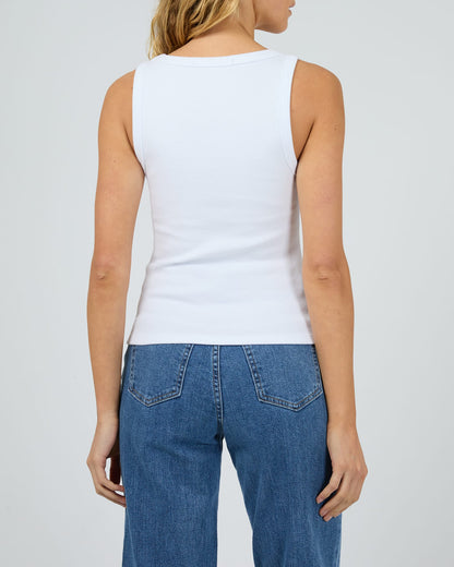 Person wearing a white sleeveless top and blue jeans on a plain background
