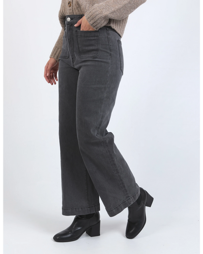 Person wearing gray wide-leg jeans and black shoes on a white background