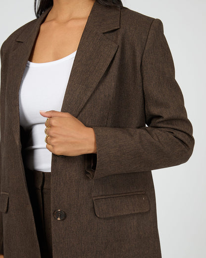 Brown blazer worn by a person on a white background