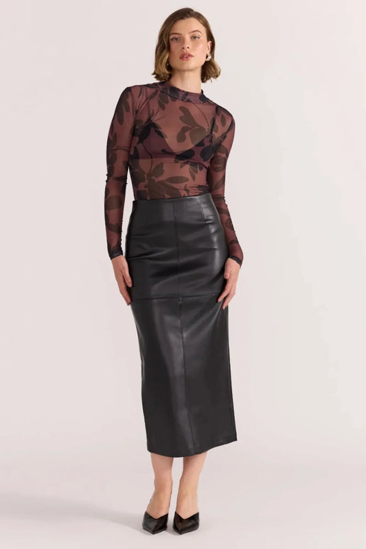 Woman wearing a patterned top and black leather skirt on a white background