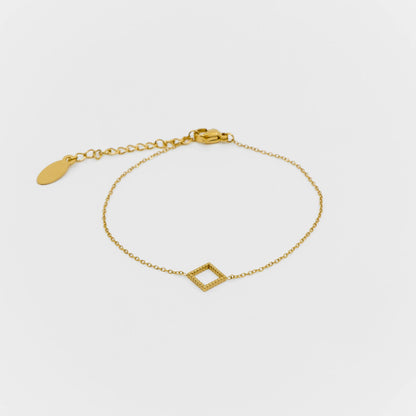 Gold bracelet with a geometric design on a light gray background