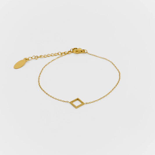Gold bracelet with a geometric design on a light gray background