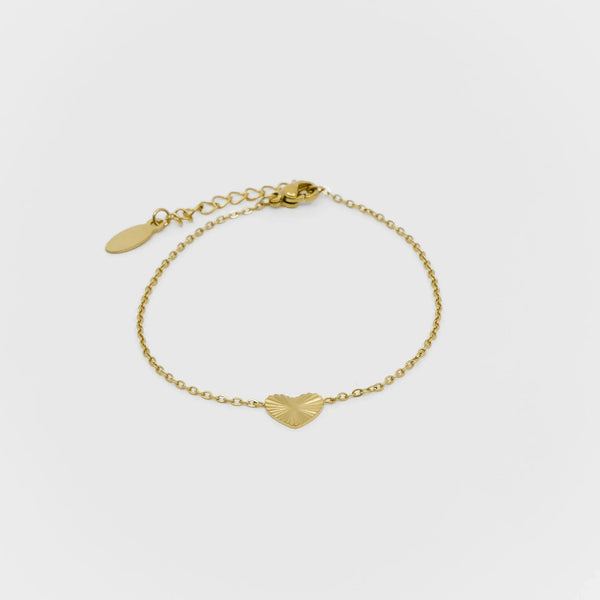 Gold bracelet with heart-shaped charms on a light gray background