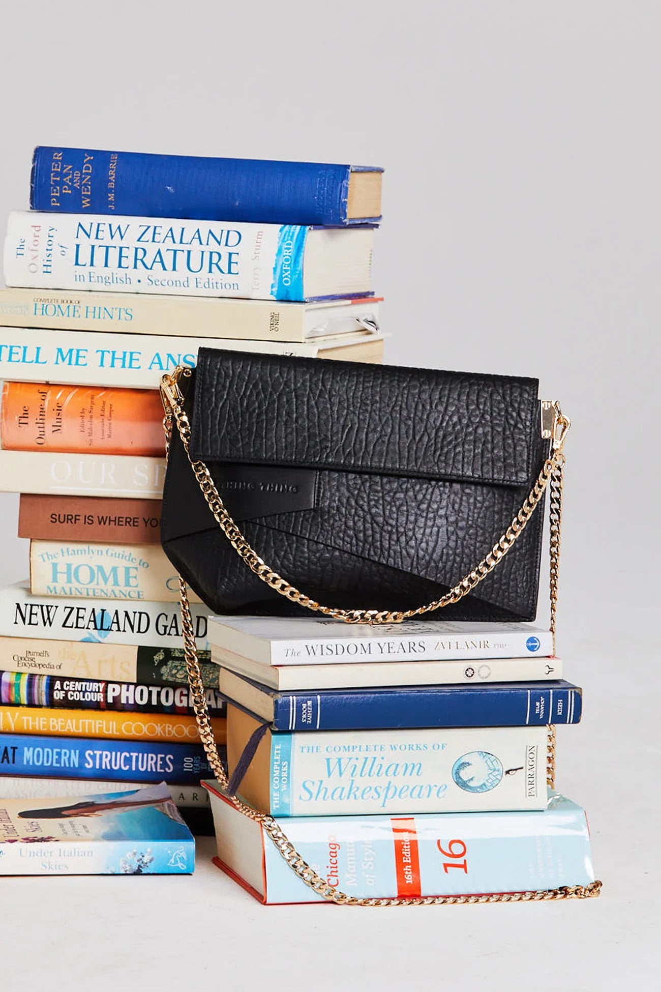 Black handbag with gold chain on a stack of books