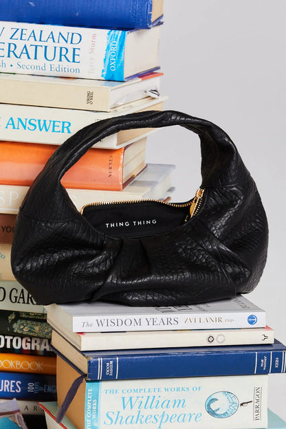 Black handbag on a stack of books with visible text