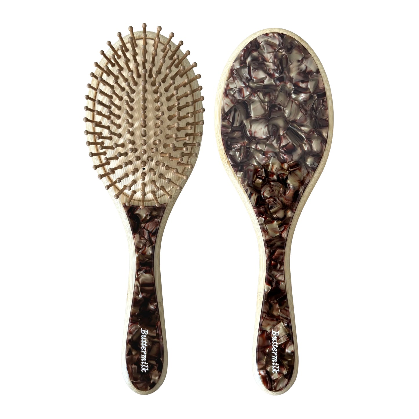 Two hairbrushes with decorative handles on a white background. Buttermilk Dev Bamboo Paddle Brush Toasted - The Rose Edit