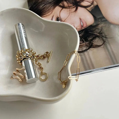 Gold jewelry on a white dish with a magazine underneath