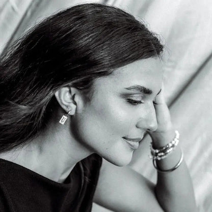 Black and white photo of a woman with jewelry, including earrings and bracelets.