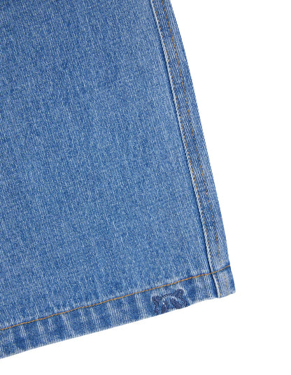Close-up of a blue denim fabric edge on a white background. Animal Crackers Era Jean Mid Blue - The Rose Edit